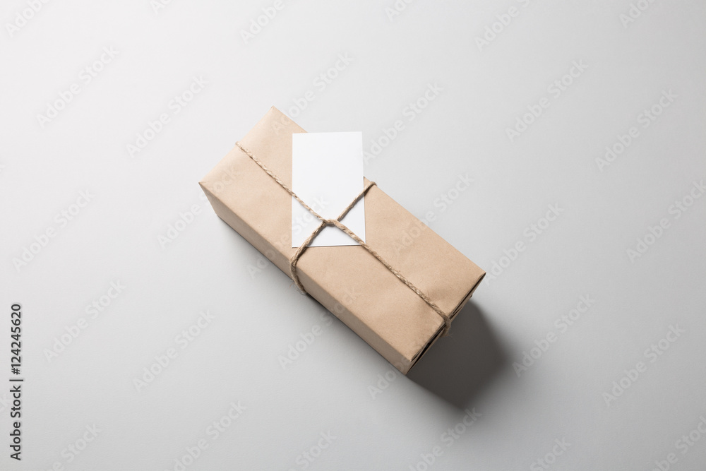 Package with rope and greeting card on gray background