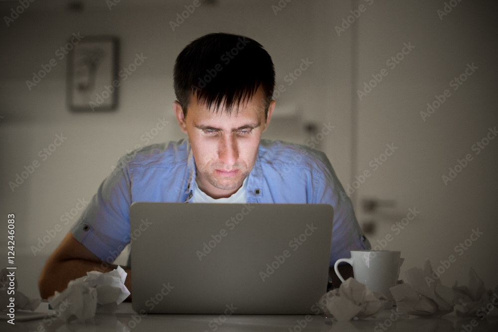 Φωτογραφία Portrait of a man at the desk working with a laptop, late at night, light glowing from the screen