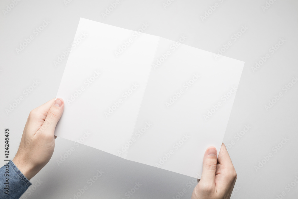 Man in blue shirt is holding a A5 Bi-Fold white paper Flyer. Man in blue shirt is holding a A5 Bi-Fold white paper Flyer.