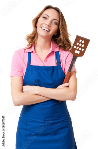 Pretty blond female woman chef mother wife in blue kitchen apron with barbecue spatula isolated on white background
