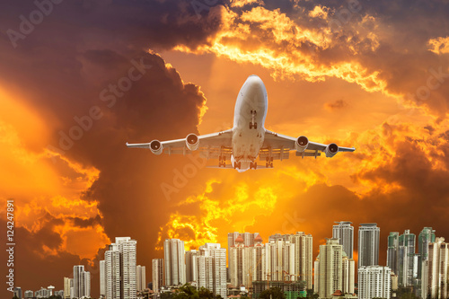 airplane flying take off from runway on sunset with modern skyscrapers background
