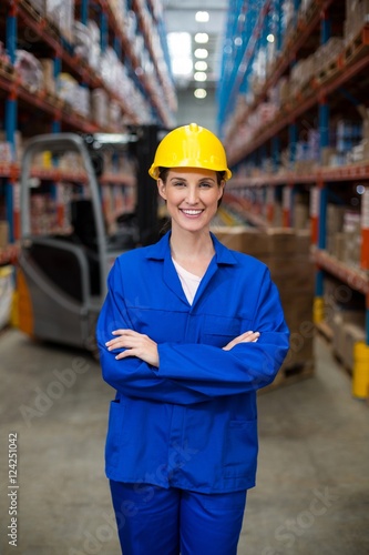 Portrait of female warehouse worker standing with arms crossed