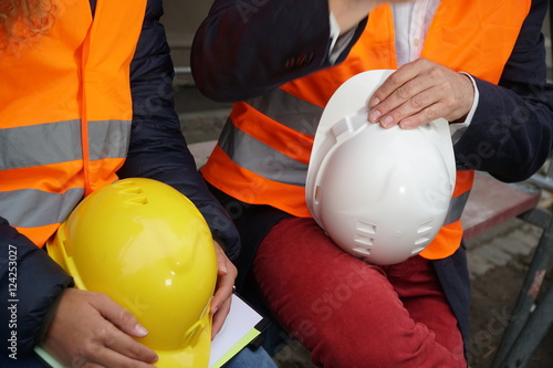 Cropped construction workers wearing safety vest holding hardhats