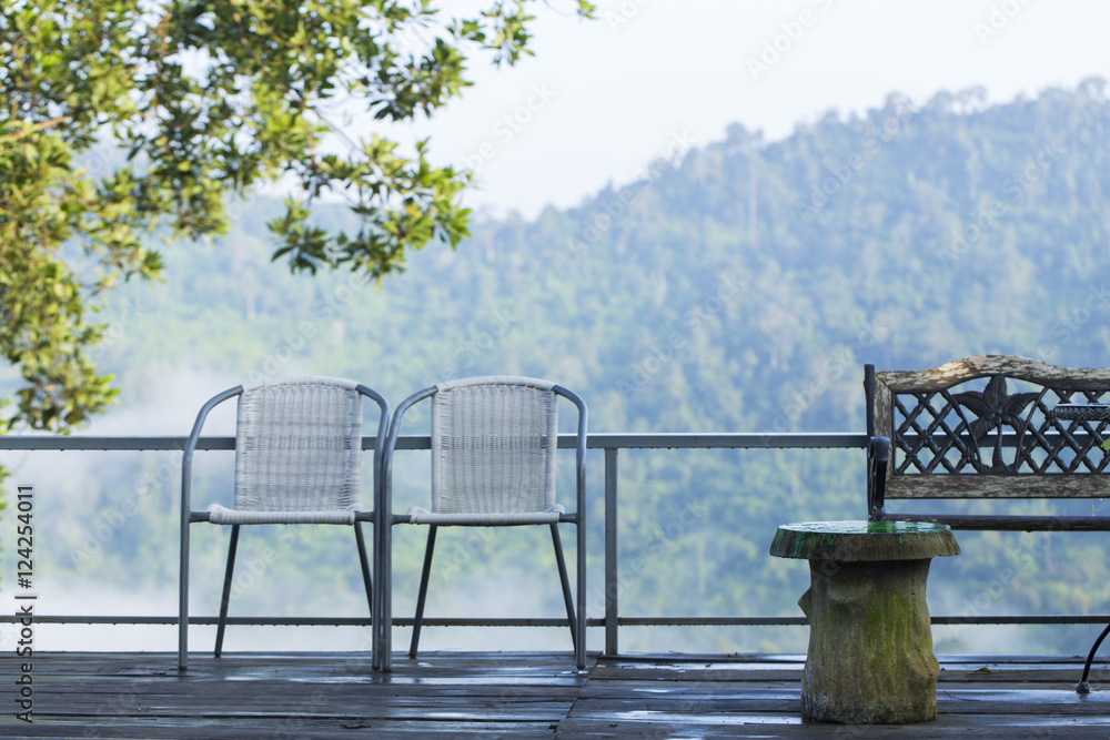 Two chairs placed side by side on the balcony. Behind the valley fog and cool.