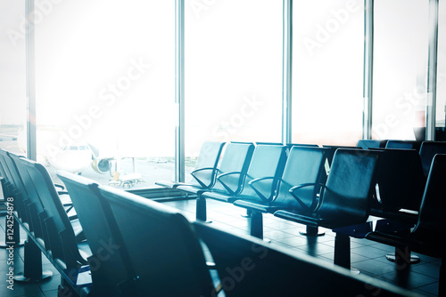 An interior of the empty concourse at the modern international airport. Empty seats at the departure gates in the airport terminal. Nobody. Horizontal photo.
