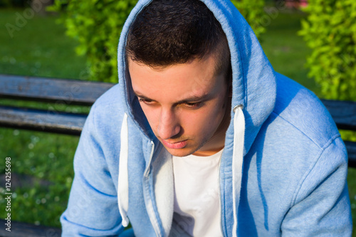 young sad boy in sweater sitting on bench