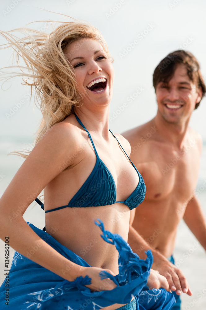 Young Couple Man and Woman Playing in Surf at Beach Young Couple Man and Woman Playing in Surf at Beach