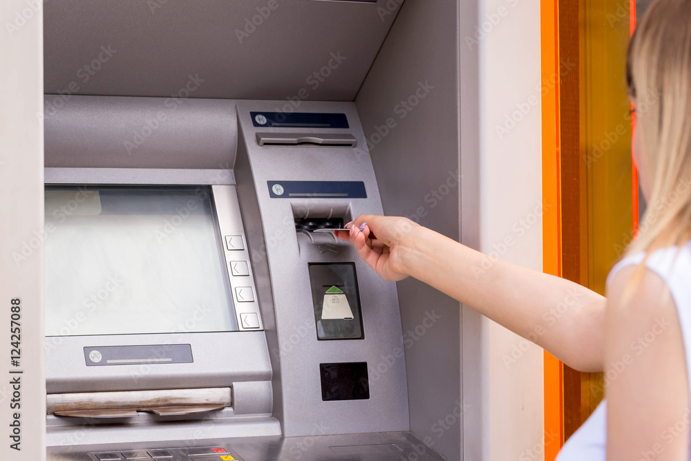 young woman inserting a credit card to ATM young woman inserting a credit card to ATM