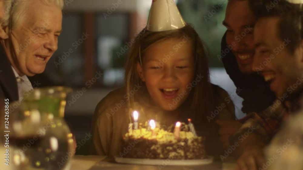 Happy Smiling Girl Blowing Candles out on her Birthday Cake. Girl Surrounded by Her Family and Friends Happy Smiling Girl Blowing Candles out on her Birthday Cake. Girl Surrounded by Her Family and Friends