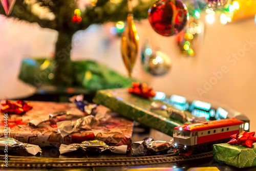 Miniature train on table under christmas tree around gifts and candys