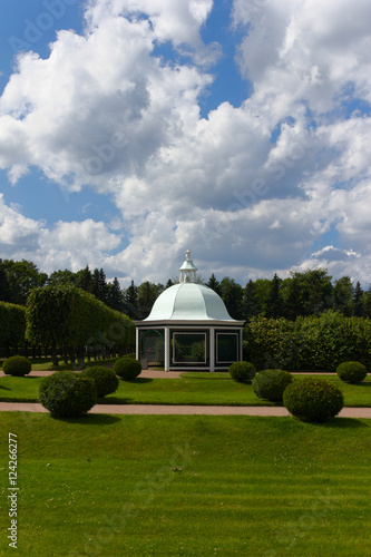 White gazebo in green park with blue sky