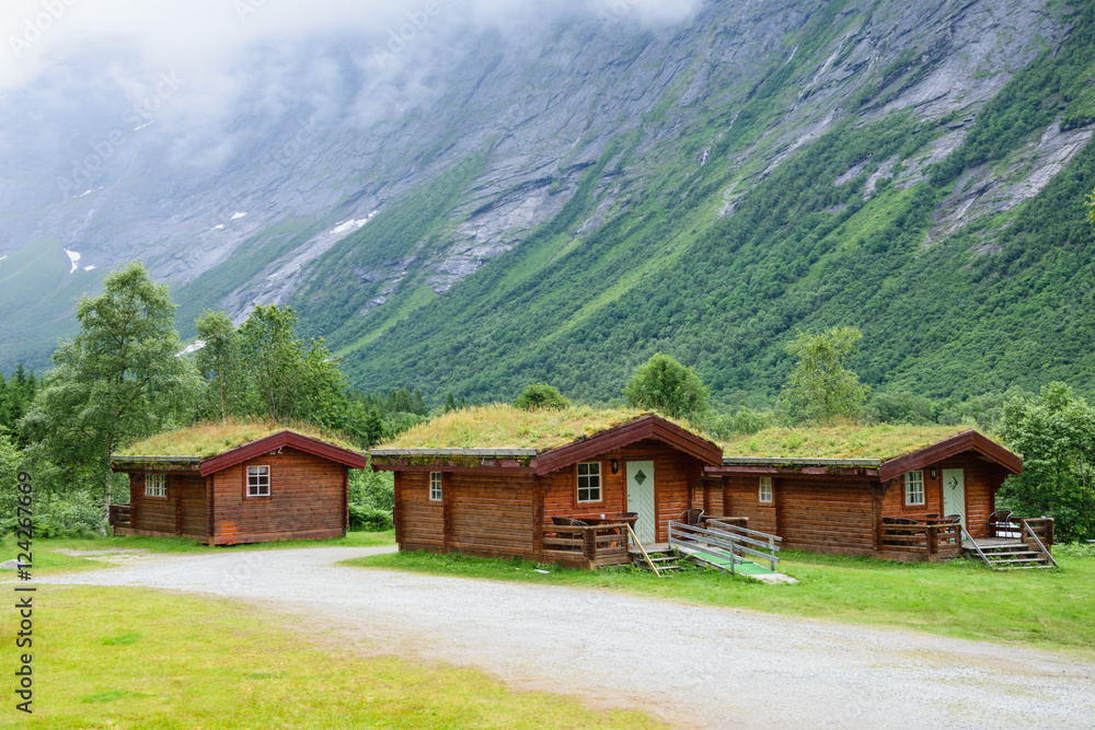 Norwegian wooden houses with grass on the roof at the foot of the mountain