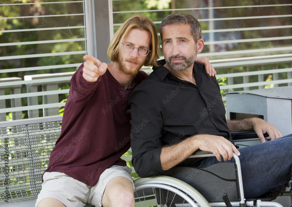 Obraz premium young man showing something to man in wheelchair