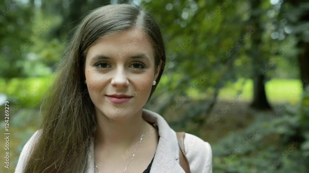 Face of beautiful young woman against green city park Face of beautiful young woman against green city park