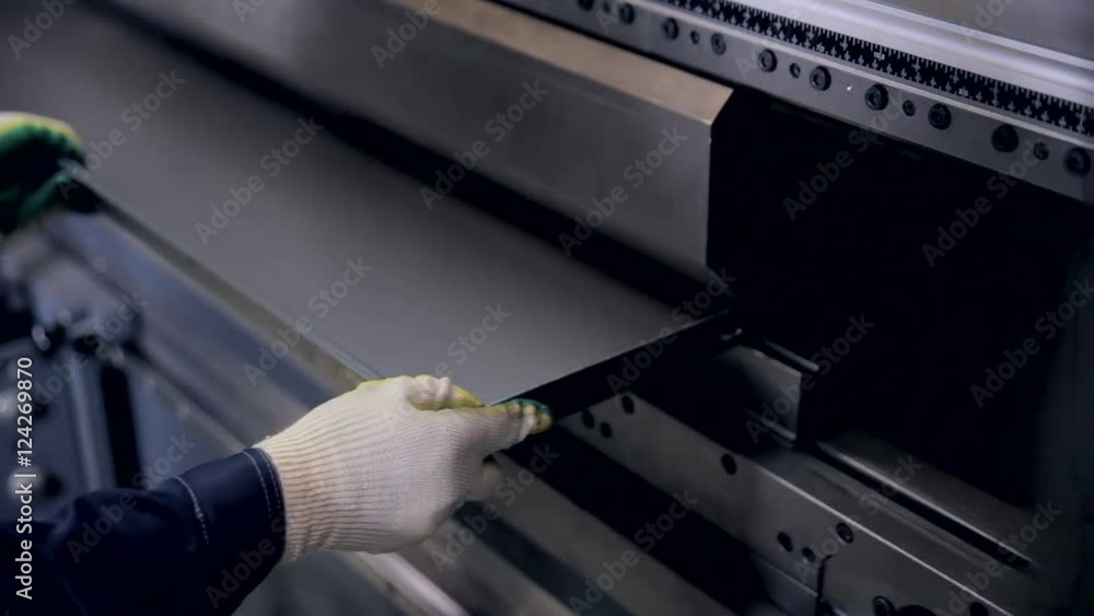 Worker hands bend metal sheet on a modern bending industrial machine at ...