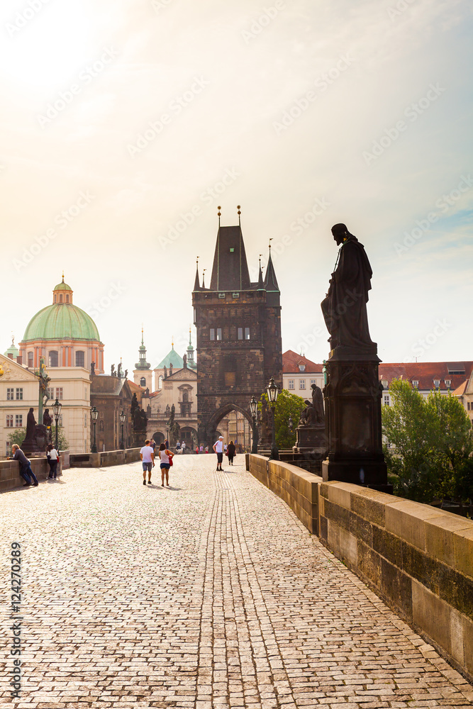 Prague, Czech Republic. Charles Bridge with its statuette, Old Town Bridge Tower, St. Francis Of Assissi Church in the background.