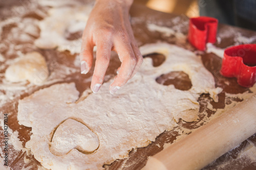 closeup of young caucasian woman making heart-shaped cookies in the kitchen