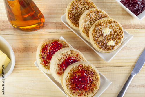 Freshly toasted crumpets with butter and jam on country table