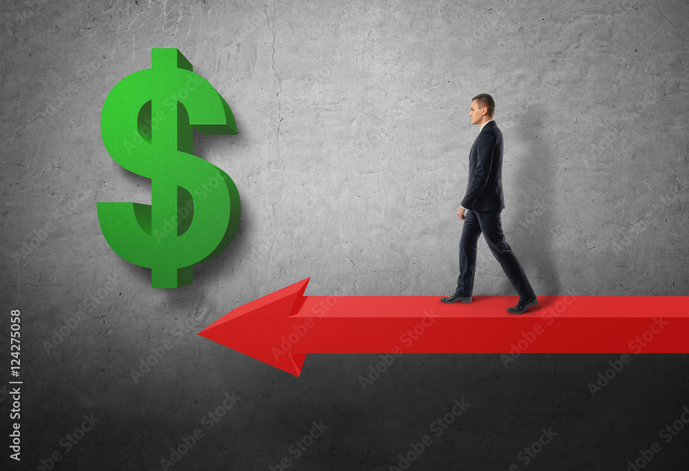 Fototapeta premium Businessman walking on big red arrow to green dollar sign