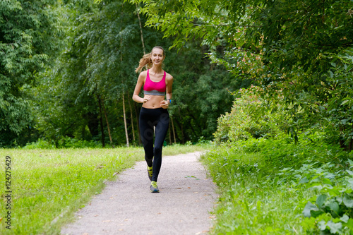 Fototapeta Naklejka Na Ścianę i Meble -  Young slim woman jogging in a park