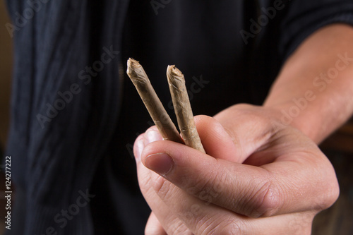 Marijuana joints in the mans hand. Man offering drugs