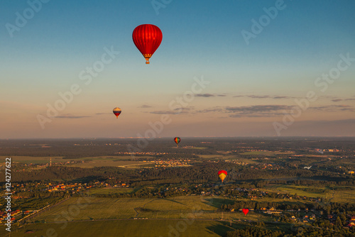 Colorful hot-air balloons are flying over the countryside