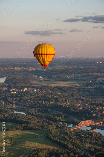 Colorful hot-air balloons are flying over the countryside © alesinya7