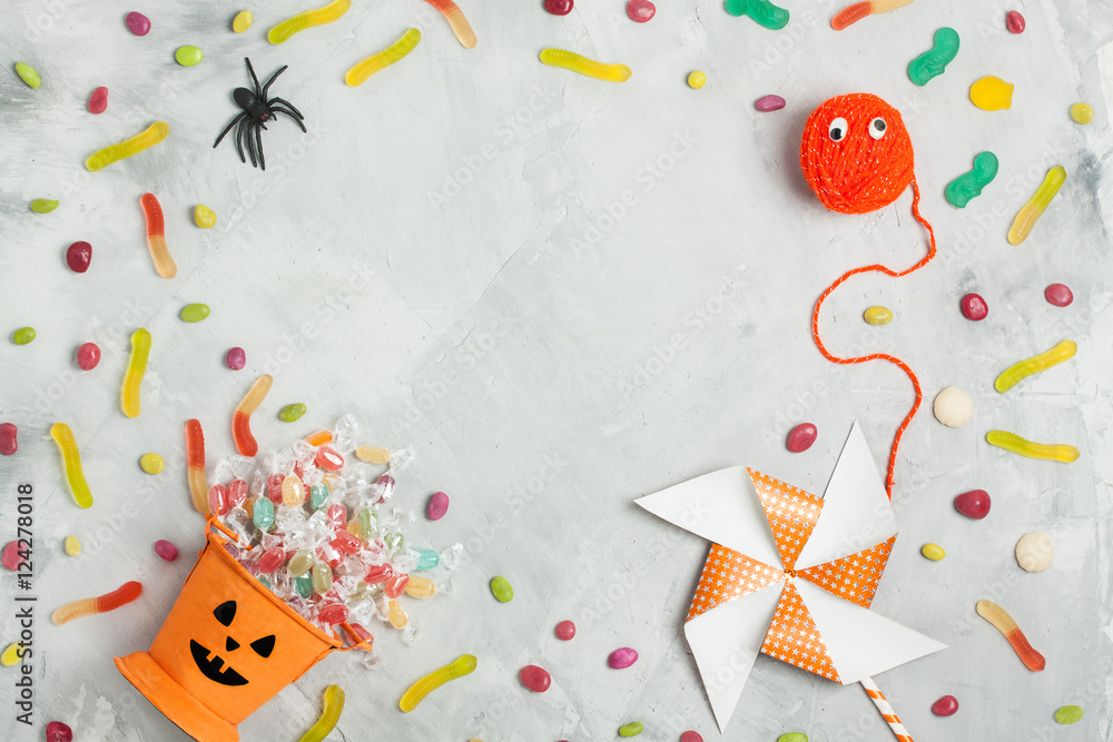 Halloween composition with orange candy bucket, jujubes, spider