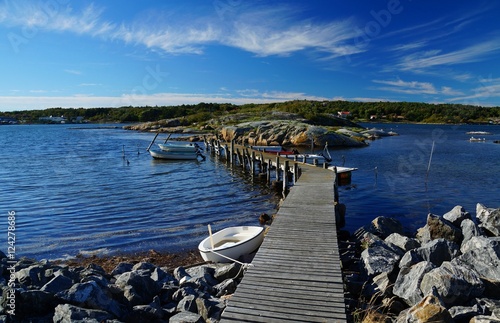 Wooden pier with small, moored ships between bare rocks on the seaside of Donsö, an island of the archipelago of Gothenburg (Göteborgs skärgård), Sweden