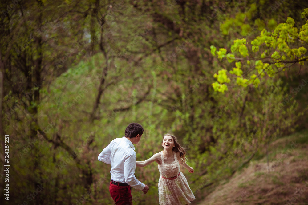 Laughing woman runs to her man across spring park Laughing woman runs to her man across spring park