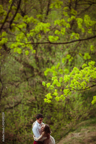 Look through the green trees at lovely couple hugging in the for © pyrozenko13