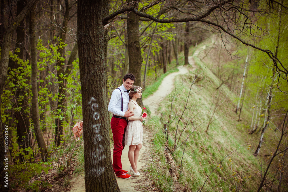 Man in red trousers and shoes hugs his lady from behind while st Man in red trousers and shoes hugs his lady from behind while st