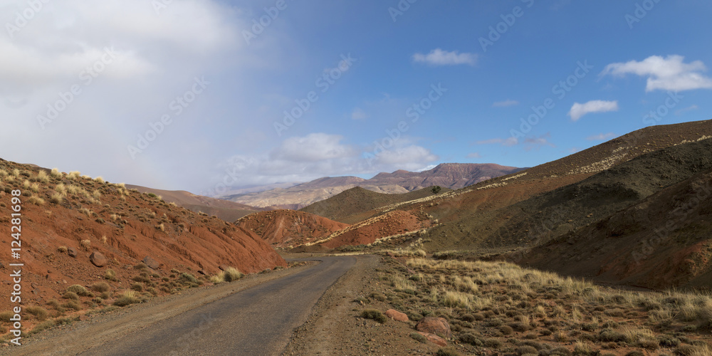 A paved road through a landscape of hills and mountains A paved road through a landscape of hills and mountains