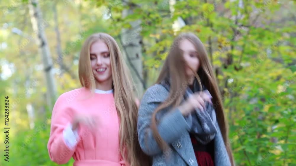Two young white girl with long thick hair dancing in the autumn on the nature