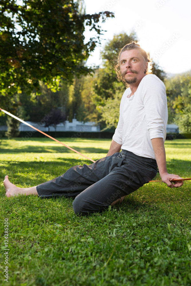 Fototapeta premium portrait of man sitting on slackline and balancing on a rope
