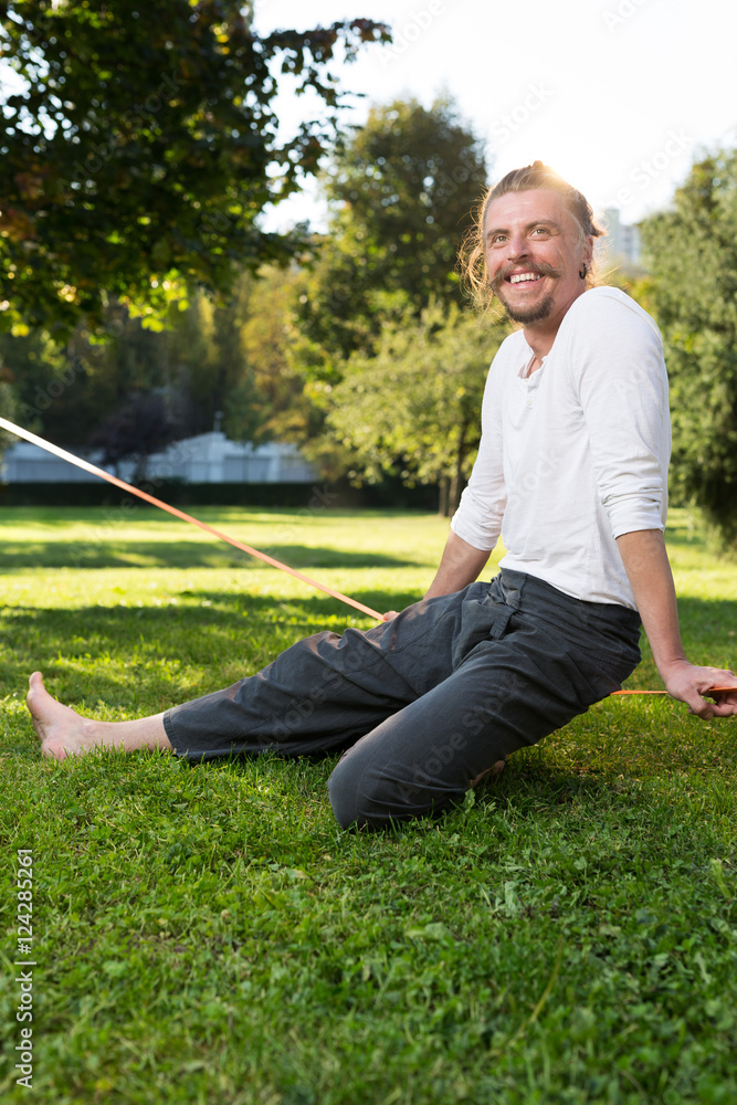 Fototapeta premium portrait of man sitting on slackline and balancing on a rope