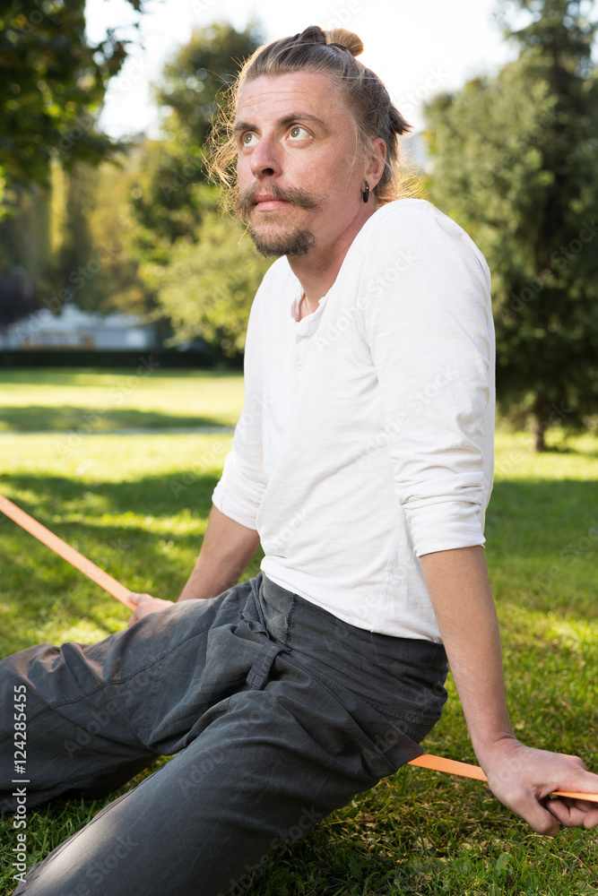 portrait of man sitting on slackline and balancing on a rope portrait of man sitting on slackline and balancing on a rope
