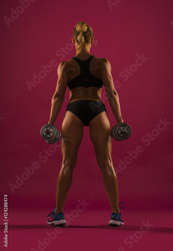 Athletic young woman showing muscles of the back and hands, isolated