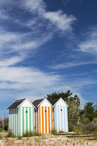 Three colourful striped painted outhouses on a sandy grassy hill with trees; Roscoff, Brittany, France photo