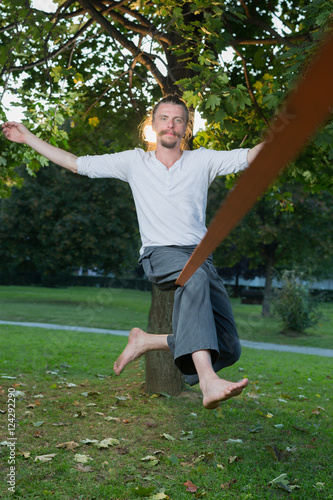 Man sitting on tightrope or slackline concentrating to keep bala