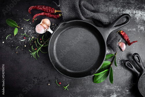 Fototapeta cast iron pan and spices on black metal culinary background, view from above
