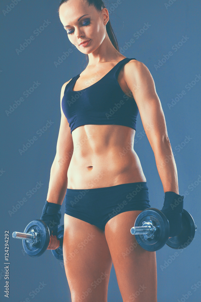 Athletic woman pumping up muscules with dumbbells Athletic woman pumping up muscules with dumbbells