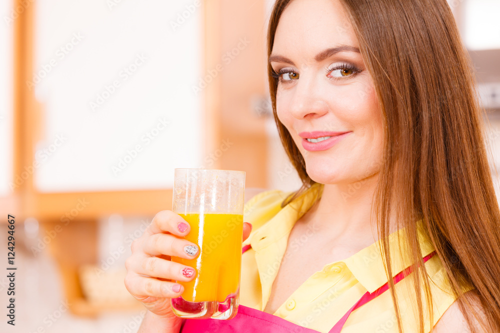 Woman in kitchen drinking fresh orange juice Woman in kitchen drinking fresh orange juice