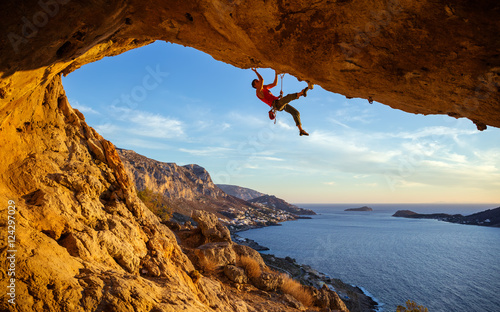 Fotobehang Male climber on overhanging rock against beautiful view of coast below