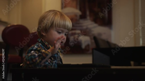 A young boy happily uses a tablet while sitting at a small table. photo