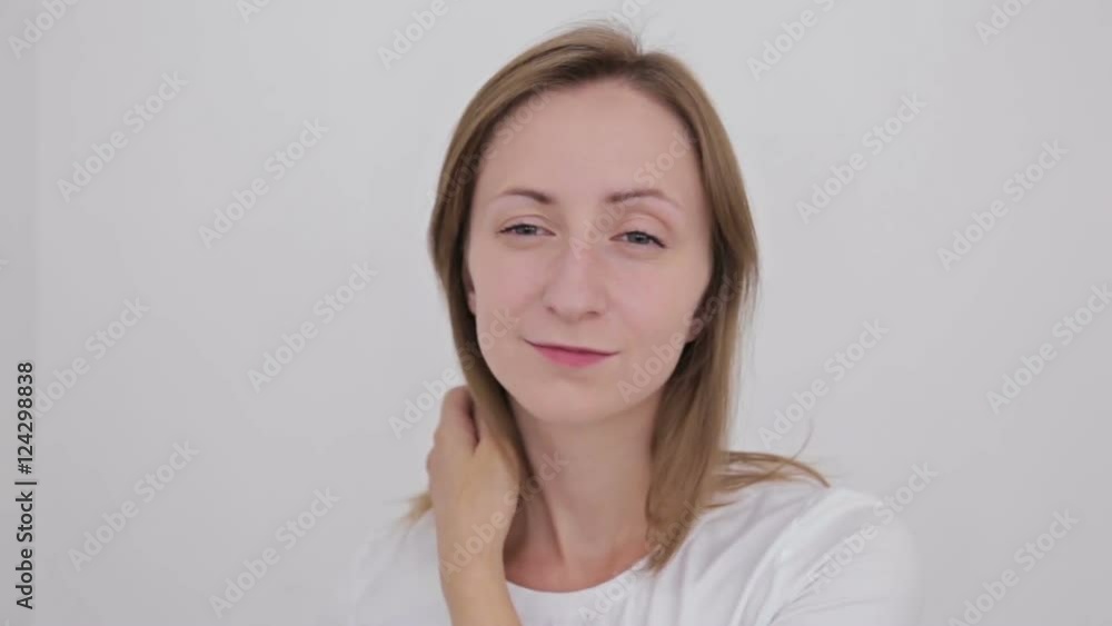Young pretty woman fixing her hair and looking at camera. White interior, makeup room Young pretty woman fixing her hair and looking at camera. White interior, makeup room