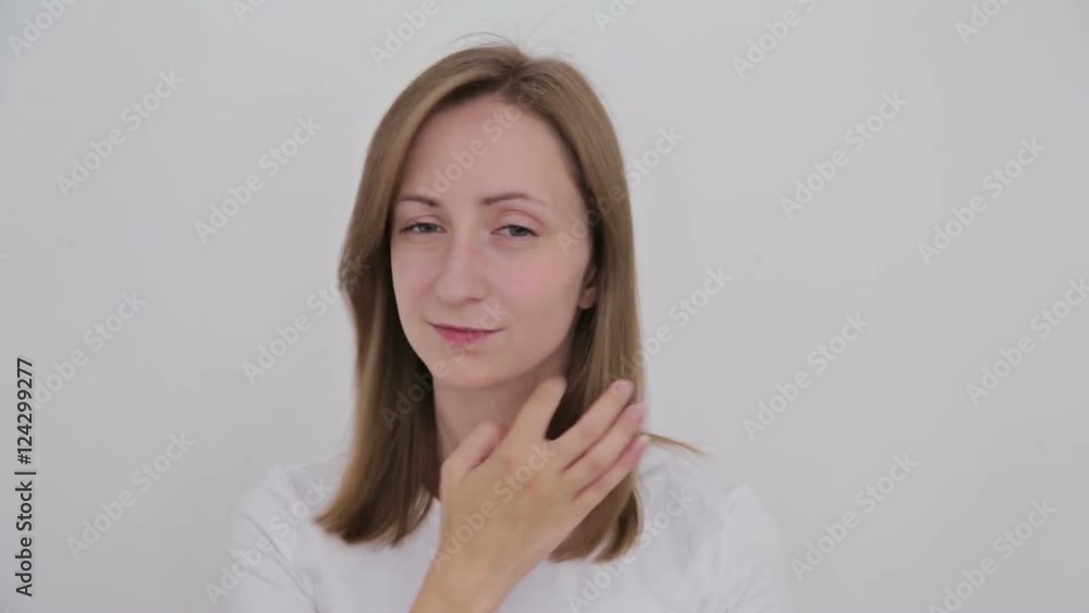 Young pretty woman fixing her hair and looking at camera. White interior, makeup room Young pretty woman fixing her hair and looking at camera. White interior, makeup room