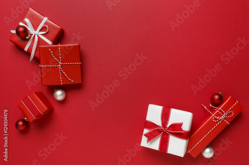Christmas gifts presents on red background. Simple, classic, red and white wrapped gift boxes with ribbon bows and festive holiday decorations. photo