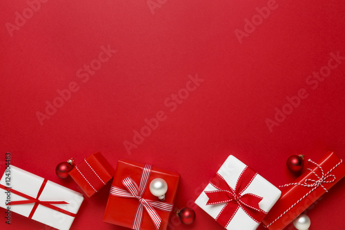 Christmas gifts presents on red background. Simple, classic red and white wrapped gift boxes with ribbon bows and festive holiday decorations. Horizontal bottom border.