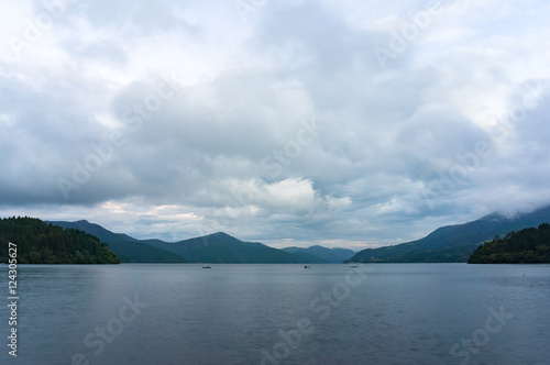 Mountain lake on dusk with fishing boats in the distance